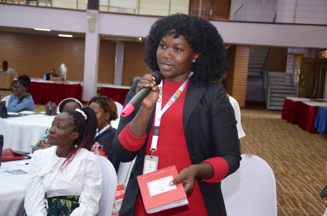 Back of a man at a concert. Hes wearing a beanie hat and a baggy denim jacket with studs. Photo with a purple hue