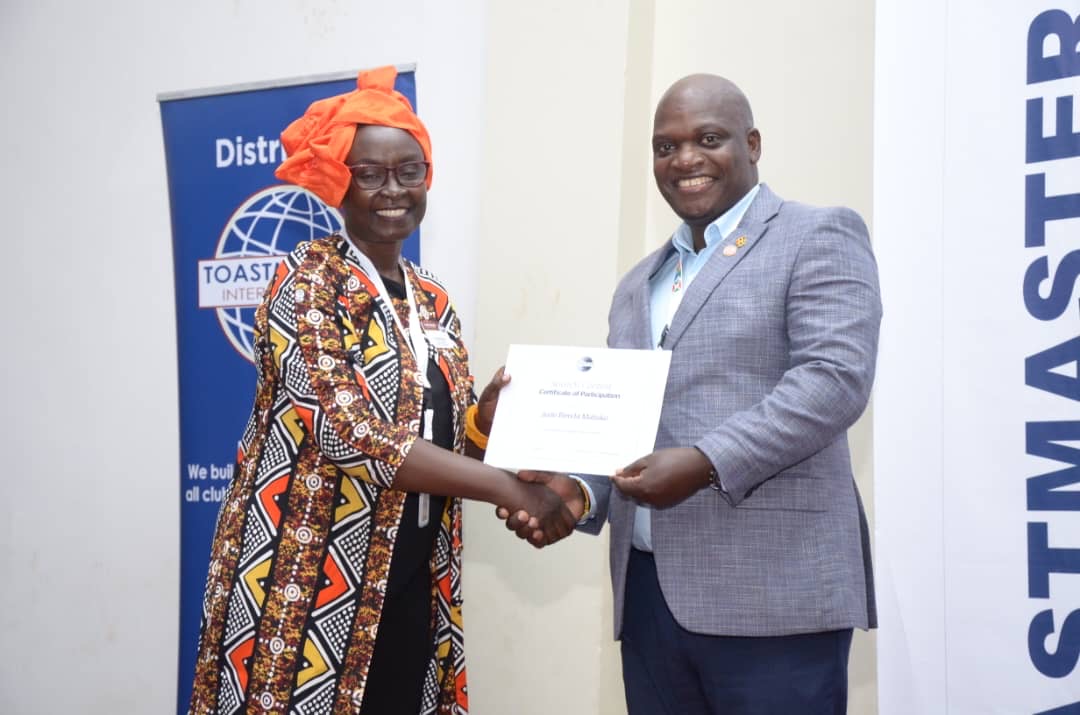 man watching a band on the stage wearing a red t-shirt and black hat.